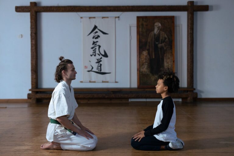 man in white robe and pants kneeling on brown wooden floor