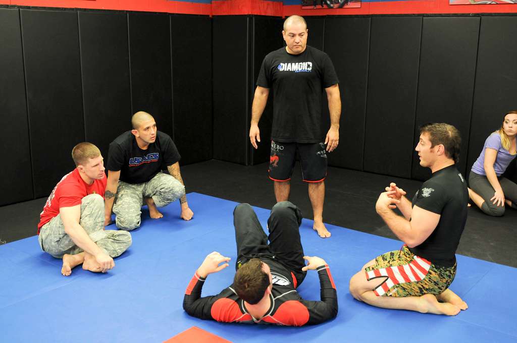 A group of martial arts students sharing talking while sitting on the mats